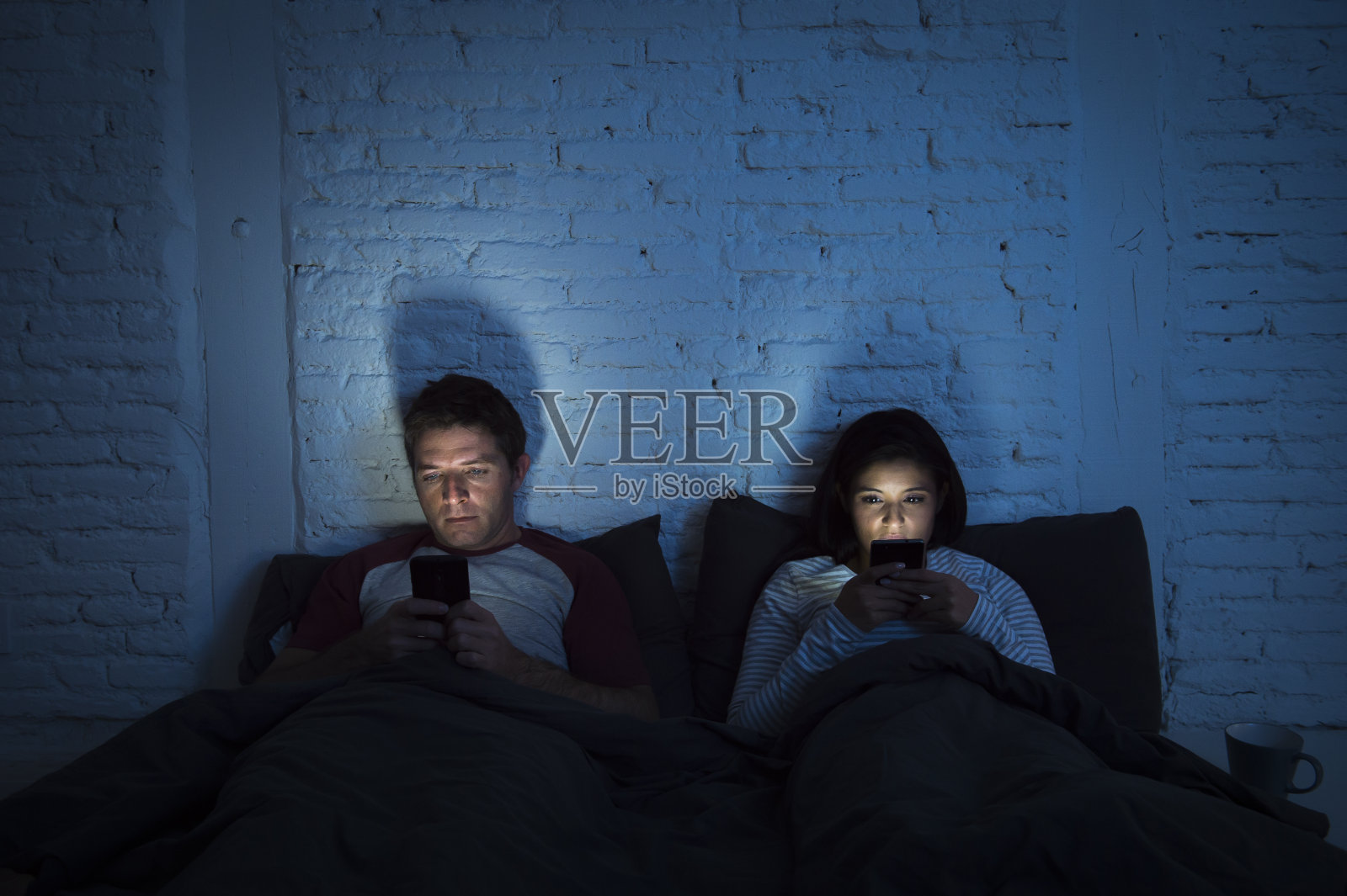 晚上夫妻在床上用手机的关系沟通问题照片摄影图片