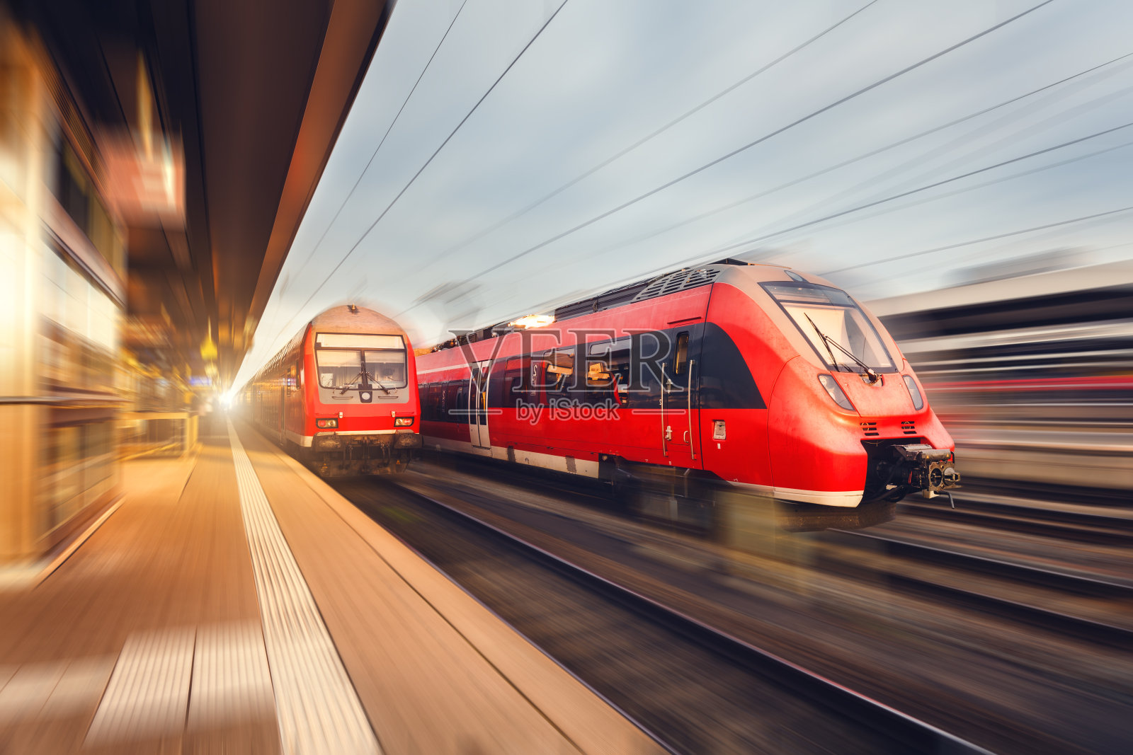 日落时分的现代高速红色客运列车。火车站照片摄影图片