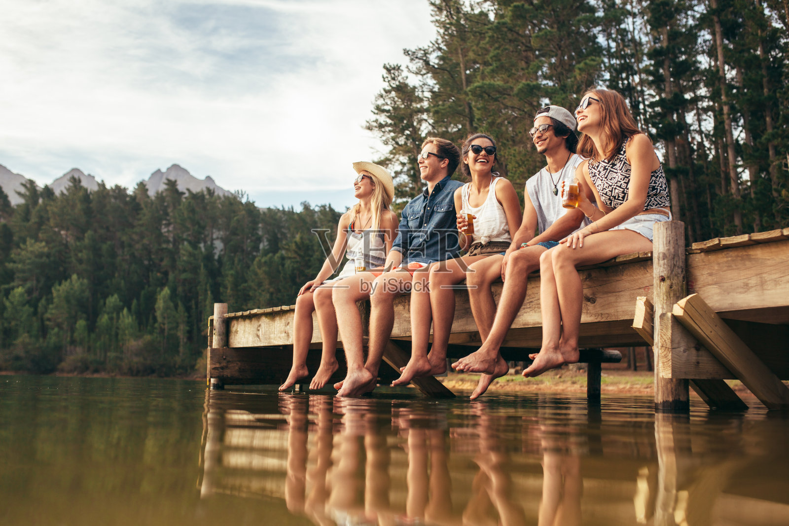 一群朋友坐在湖边的码头上照片摄影图片