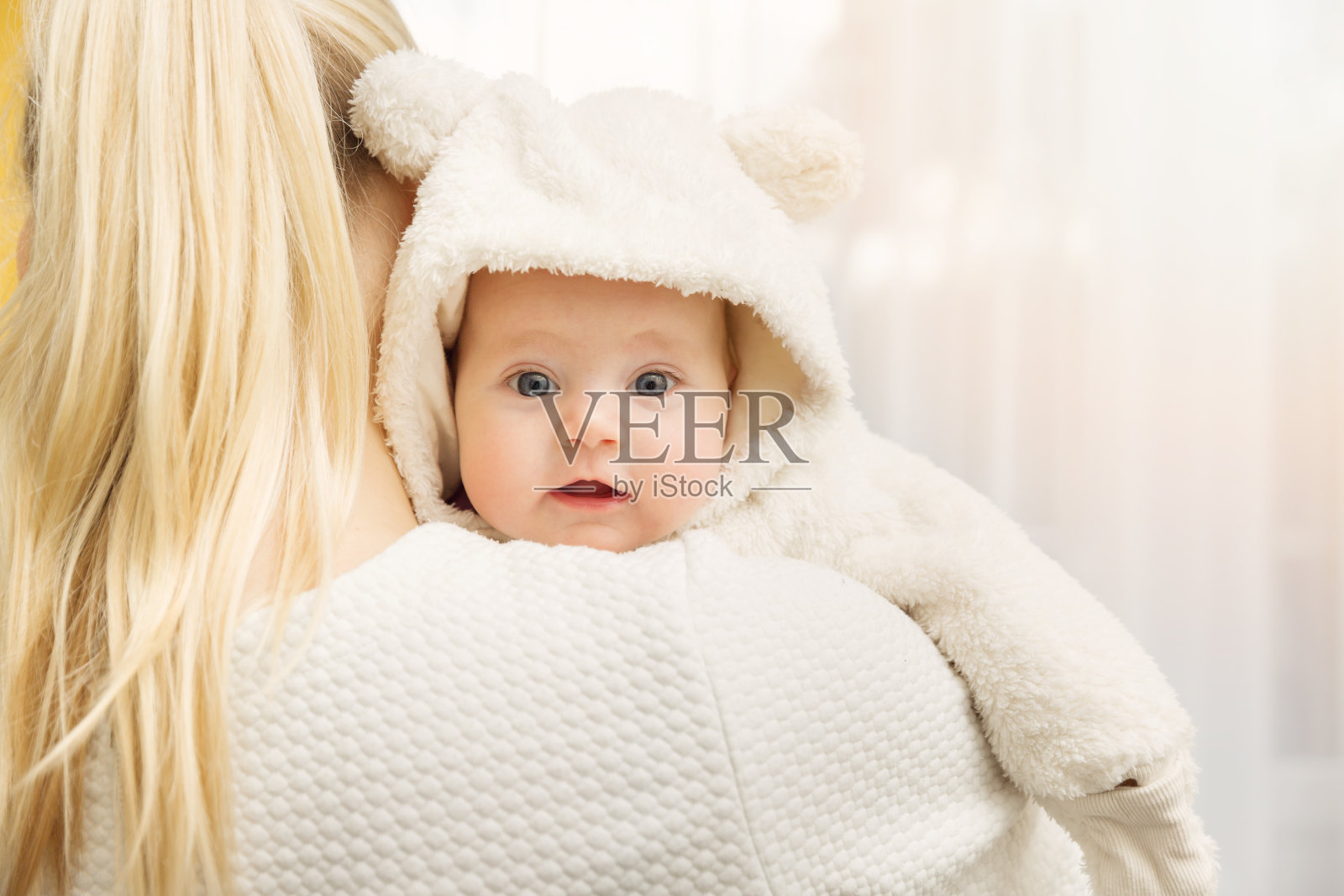 妈妈和她的宝宝在肩上穿着毛绒熊服装照片摄影图片