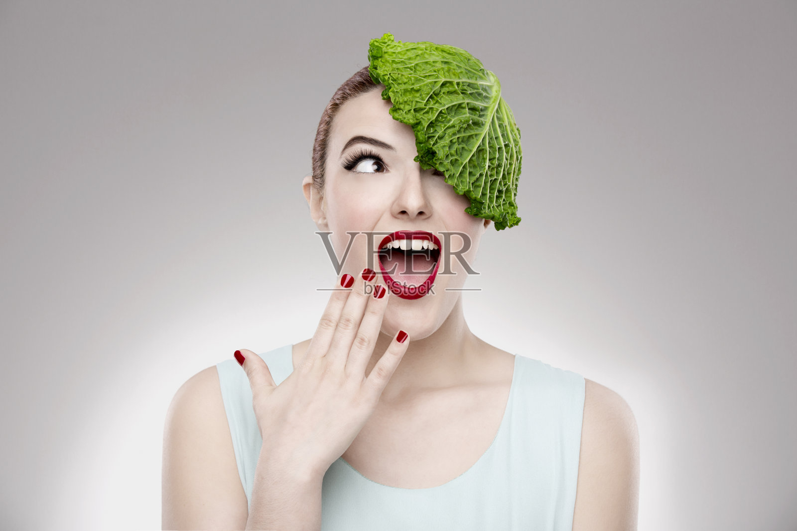 这是一个女人的肖像，她头上顶着一颗卷心菜，说明了素食主义的概念照片摄影图片