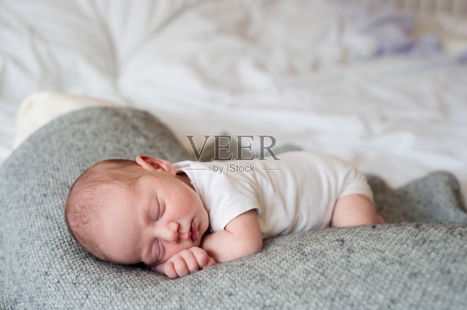 刚出生的男婴躺在床上，睡着了照片摄影图片