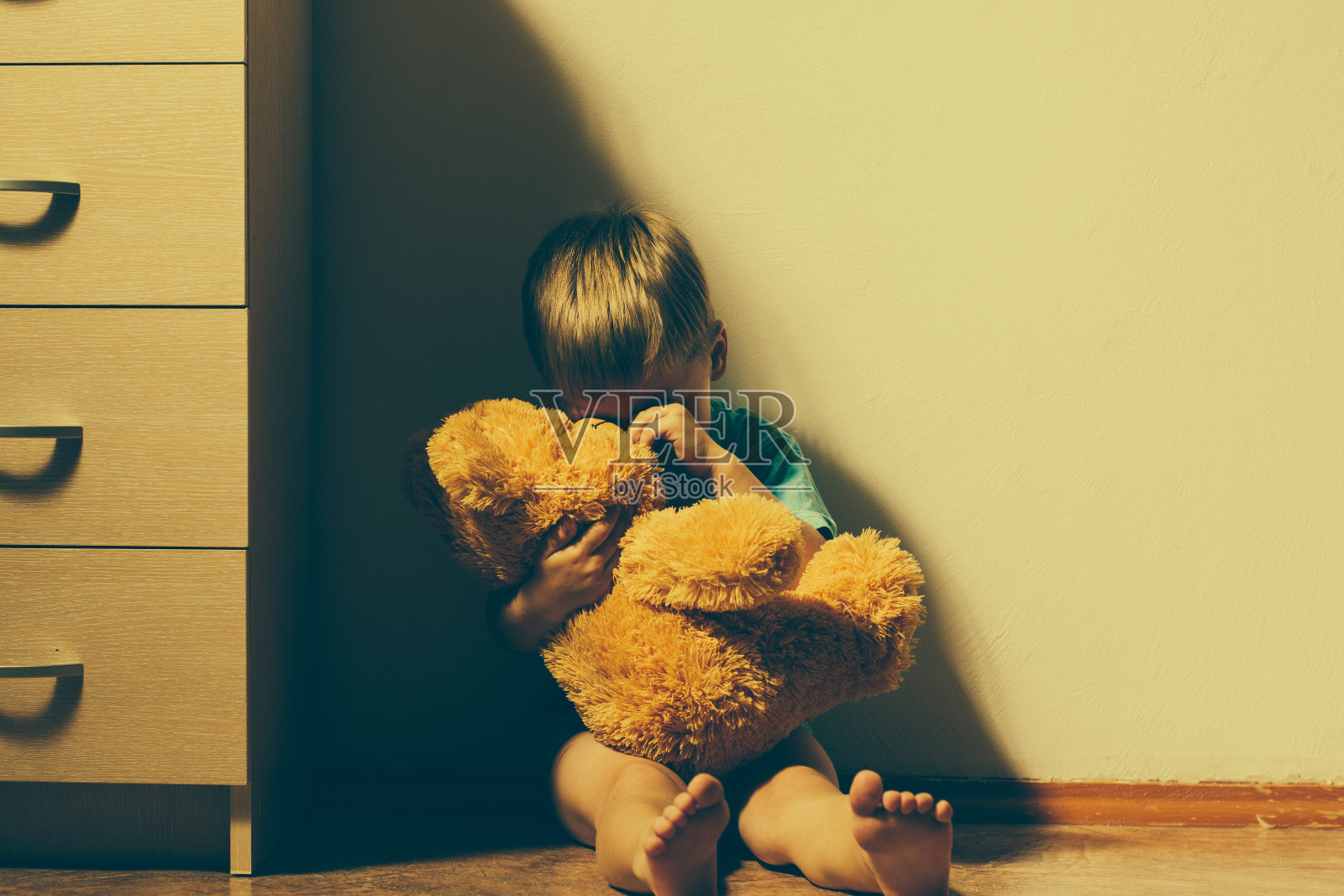 受惊的小男孩抱着他的泰迪熊哭了照片摄影图片