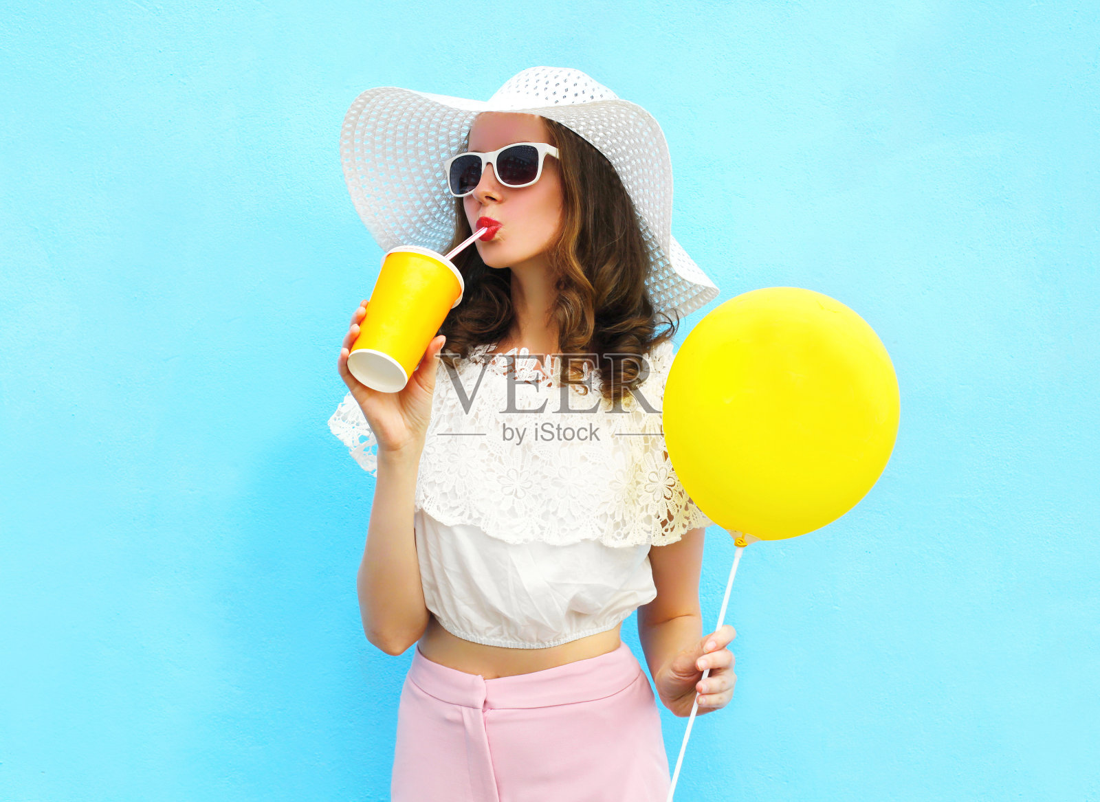 戴草帽的女子用气球喝果汁杯照片摄影图片