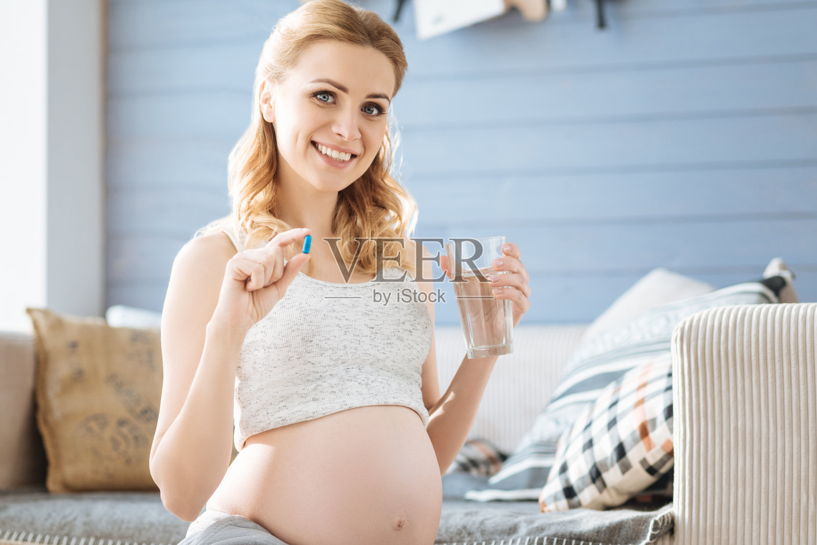 一名孕妇展示一粒药丸和一杯水照片摄影图片