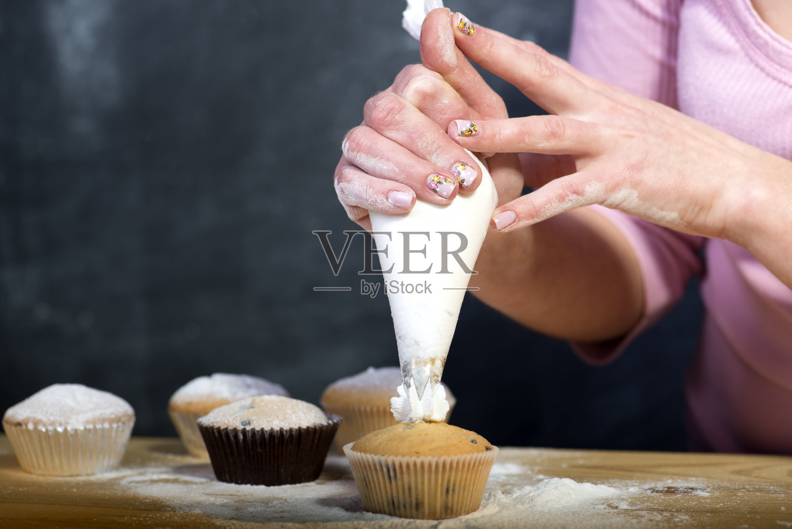 女面包师用手装饰纸杯蛋糕照片摄影图片