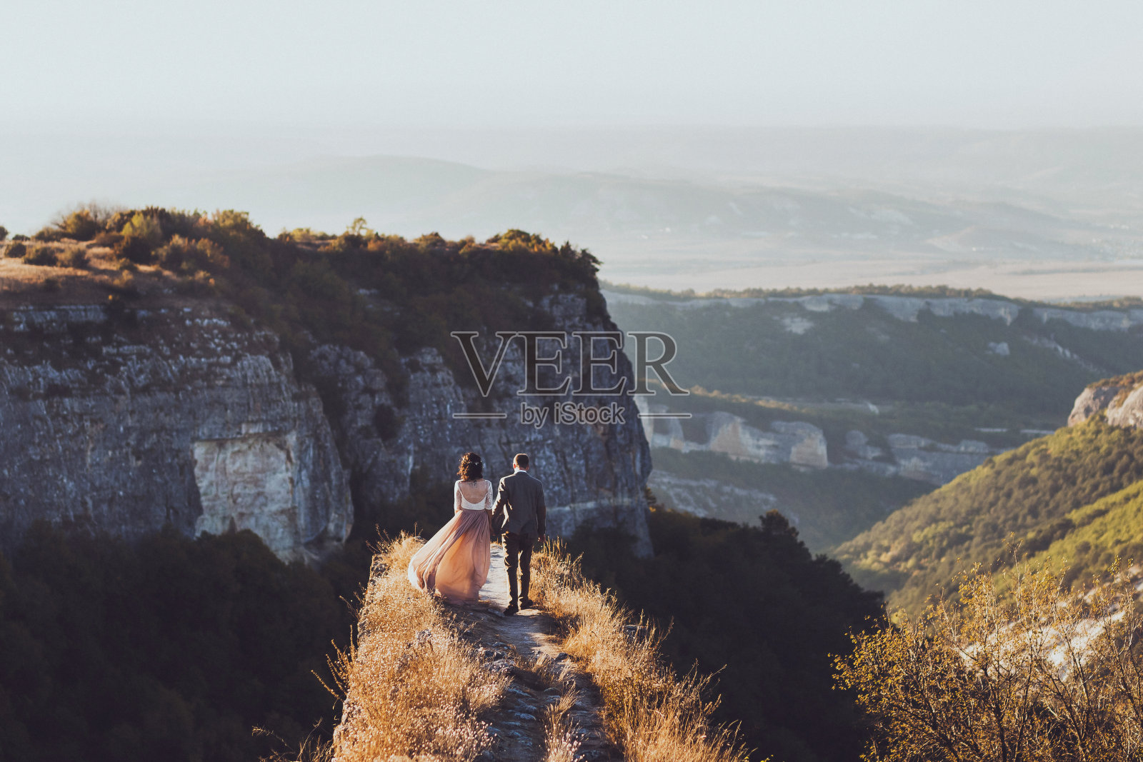 新娘和新郎走在夕阳下的山上照片摄影图片