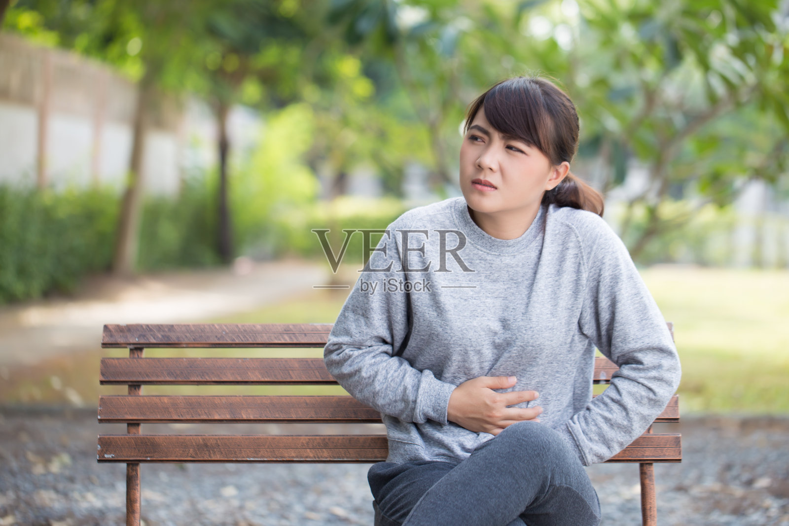 女人在公园里胃痛照片摄影图片