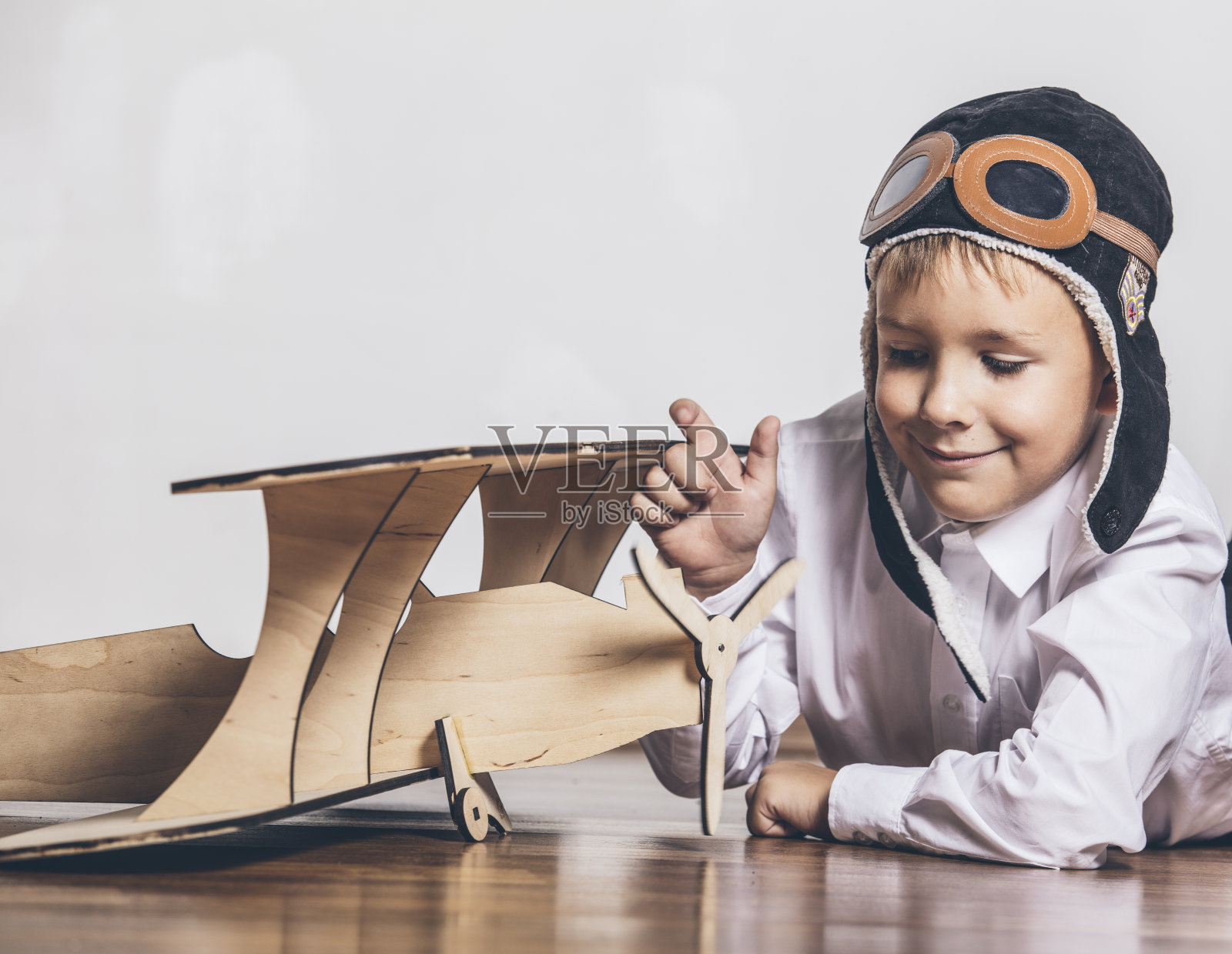 带着木制飞机模型的男孩戴着一顶帽子照片摄影图片
