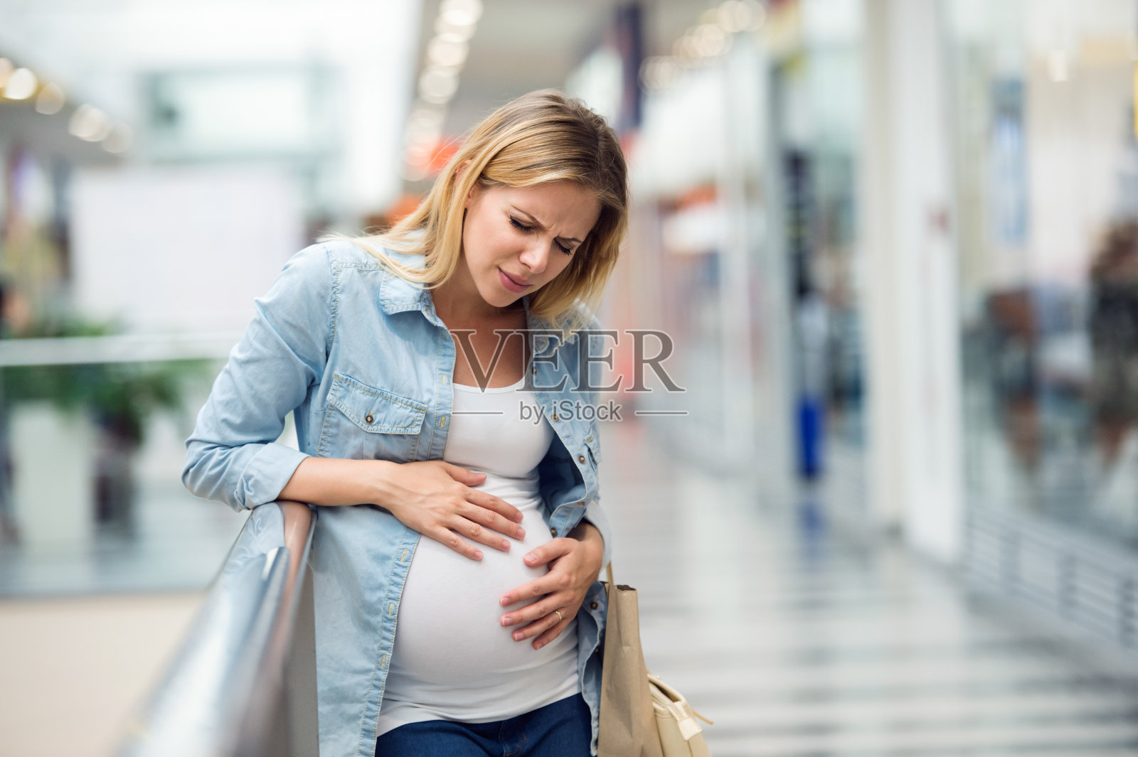 孕妇摸着肚子，很痛照片摄影图片