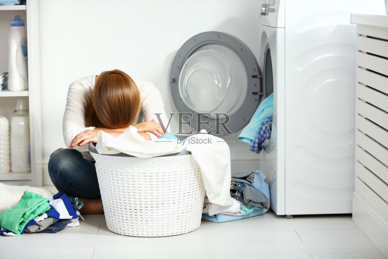 又累又不开心的家庭主妇把衣服叠进洗衣机里照片摄影图片