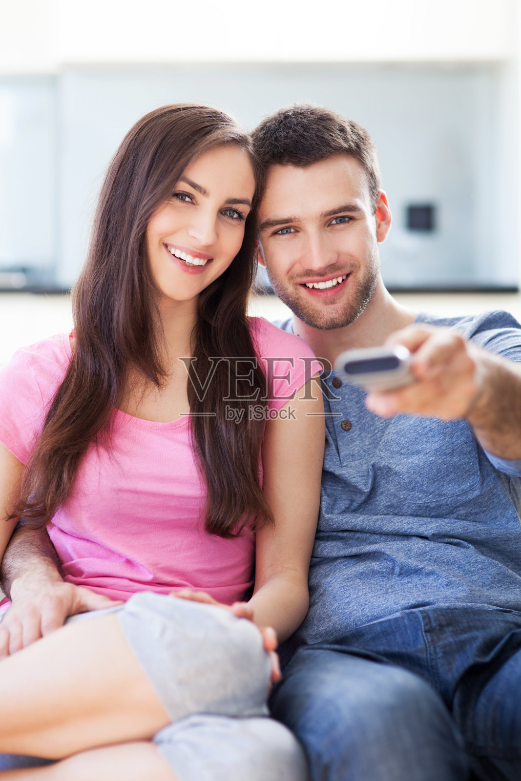 年轻夫妇拿着电视遥控器照片摄影图片