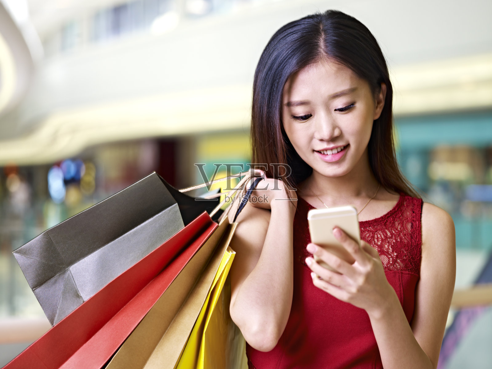 年轻的亚洲女子在购物时使用手机照片摄影图片