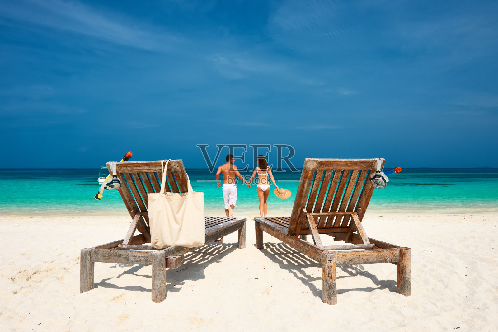 一对穿着白色衣服的夫妇在马尔代夫的海滩上跑步照片摄影图片