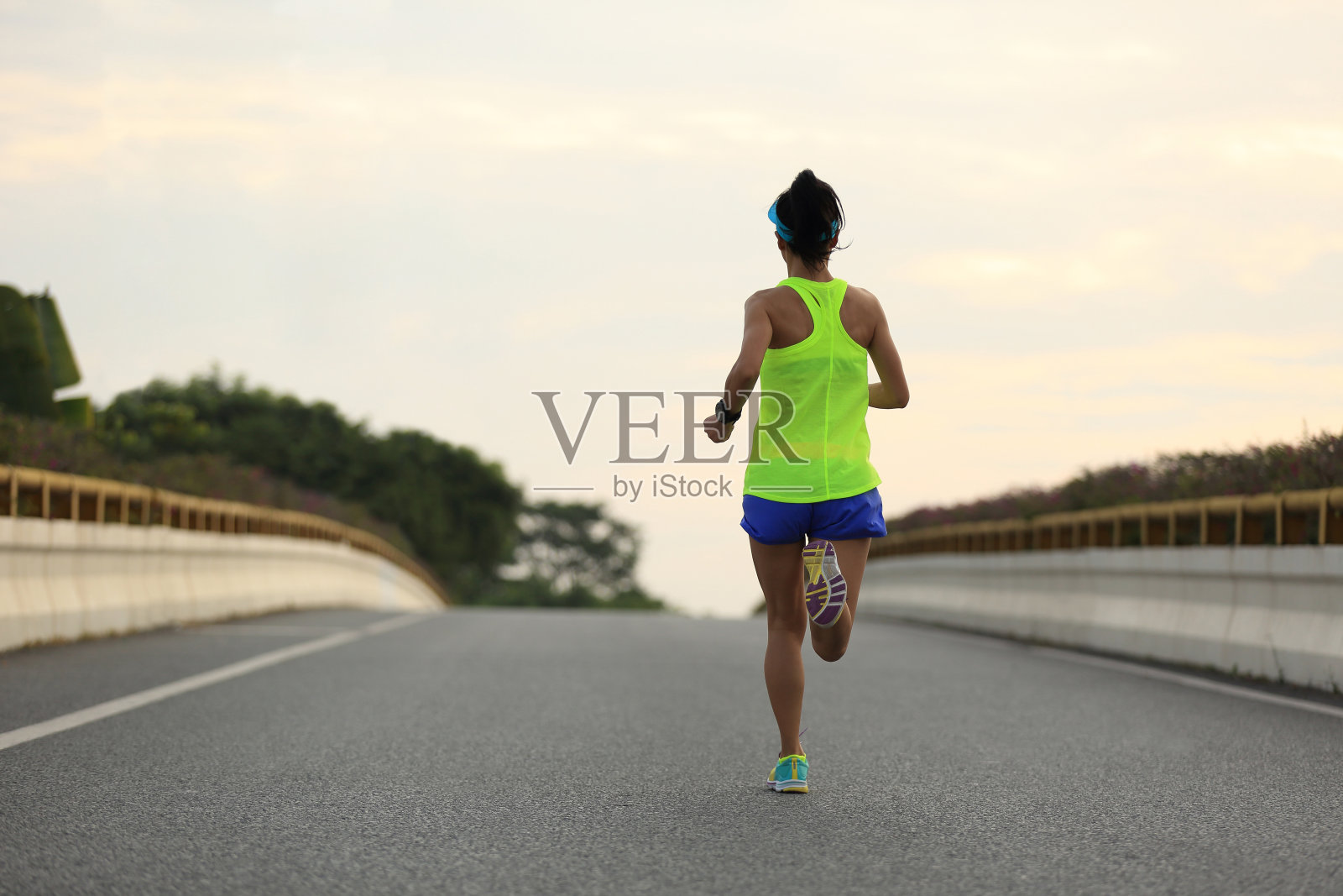 年轻的健身亚洲女人跑在城市道路上照片摄影图片