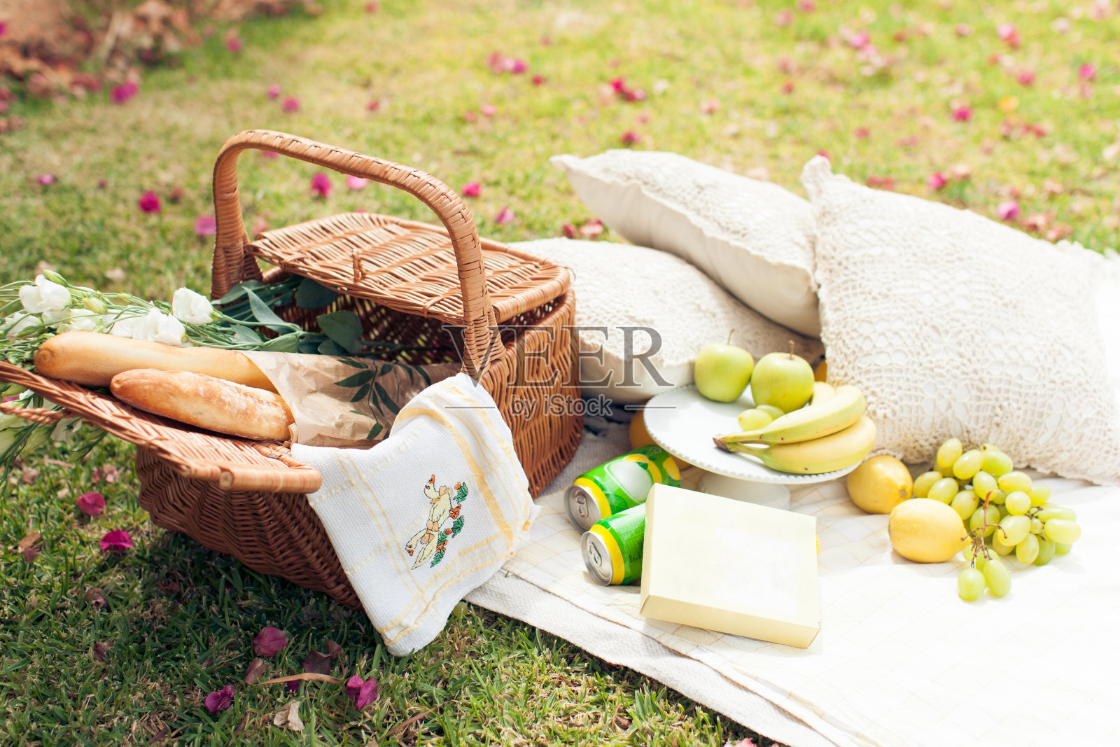 在草地上野餐。草篮，花，水果和面包照片摄影图片