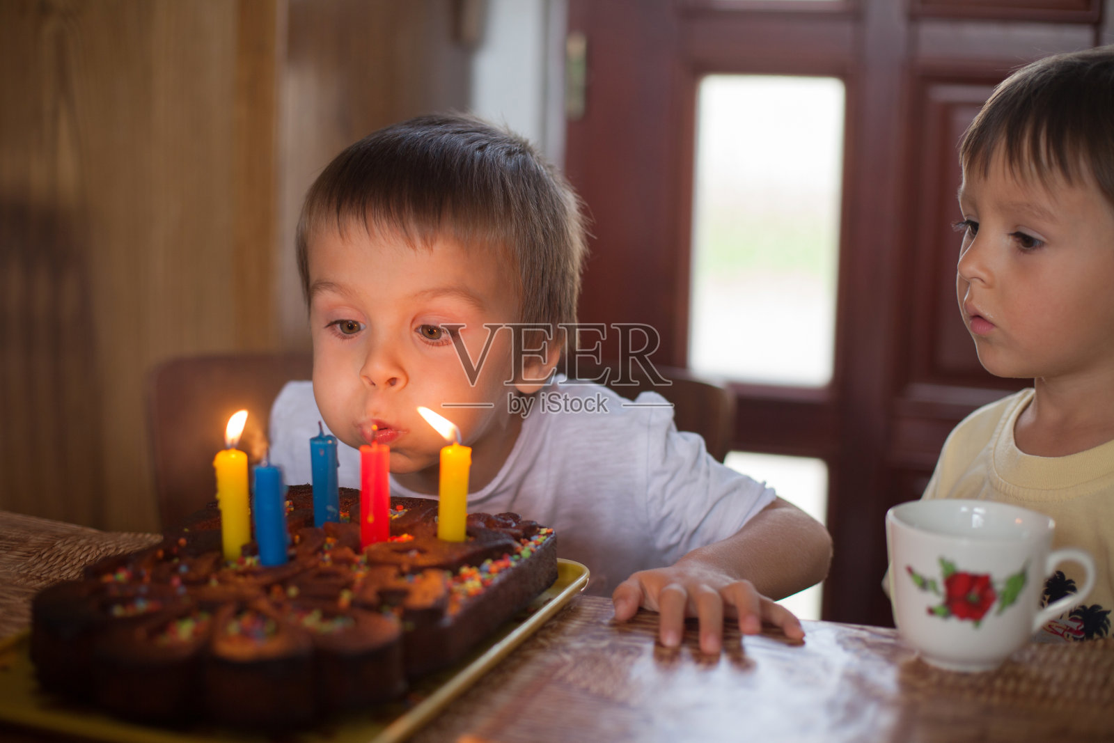 可爱的五岁男孩庆祝他的生日和吹照片摄影图片