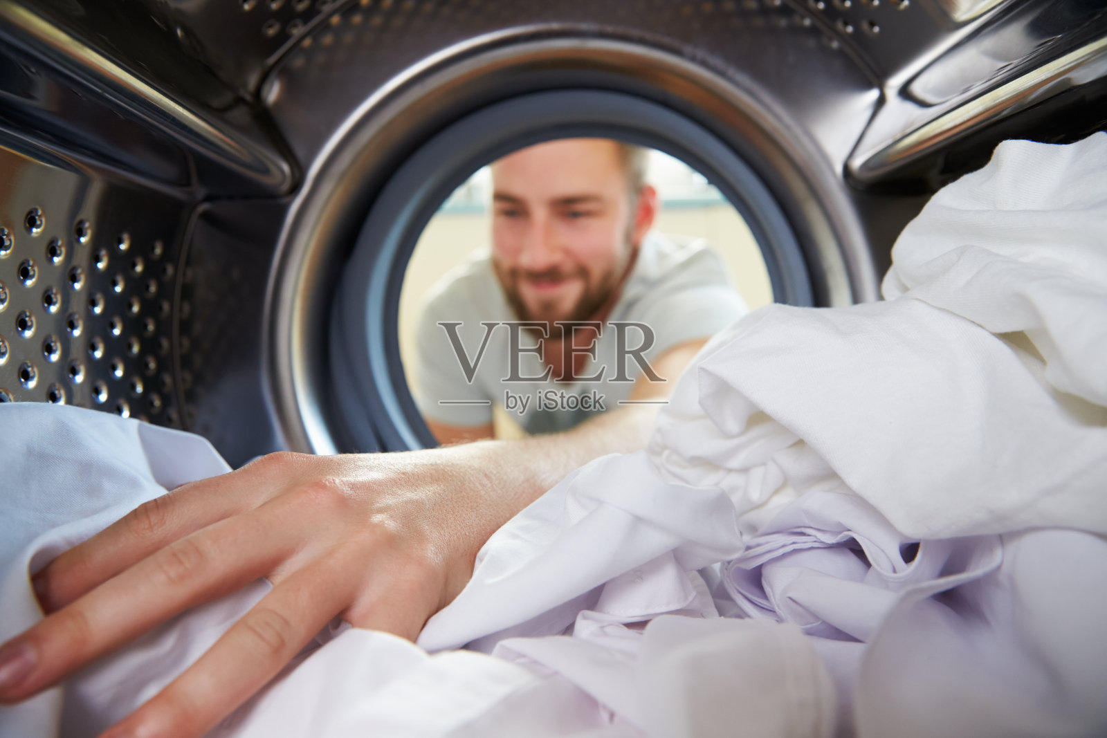 洗衣服的人把手伸进洗衣机里照片摄影图片