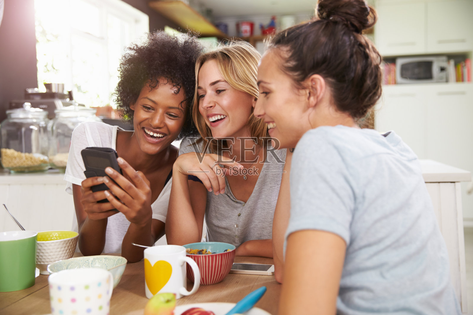 三位年轻女性朋友一边吃饭一边用智能手机照片摄影图片
