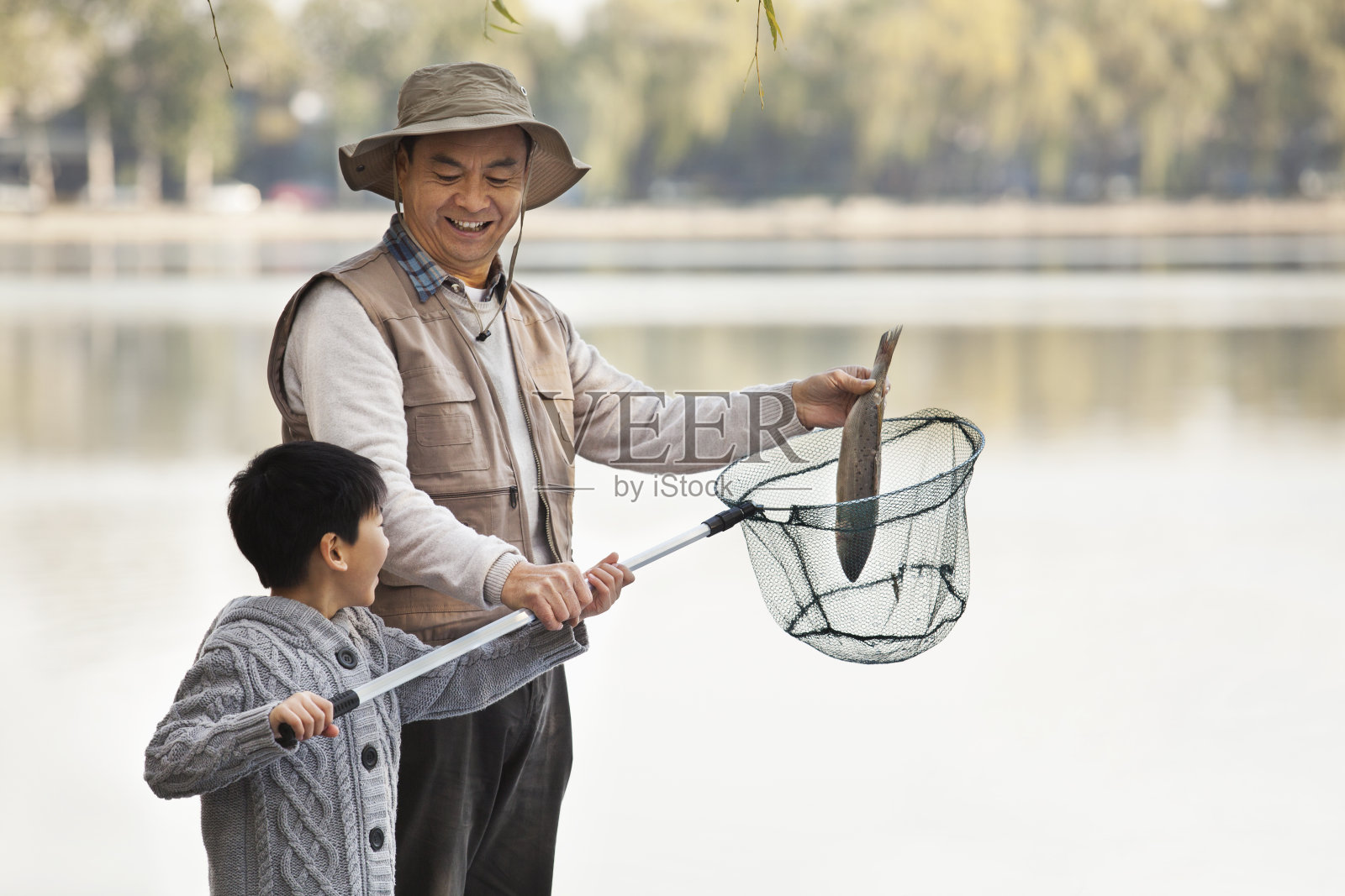 爷爷和孙子在湖里撒网捕鱼照片摄影图片