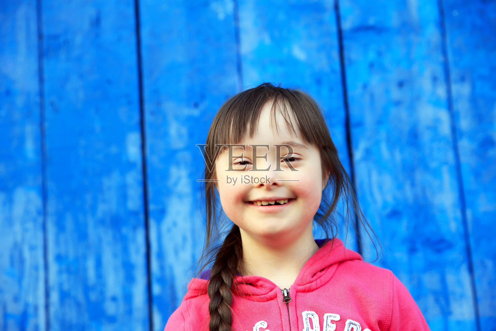 年轻的女孩在蓝色的墙壁上微笑照片摄影图片