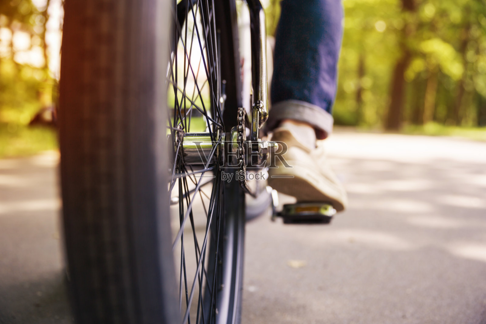 自行车轮子和男人的腿踩在踏板上照片摄影图片