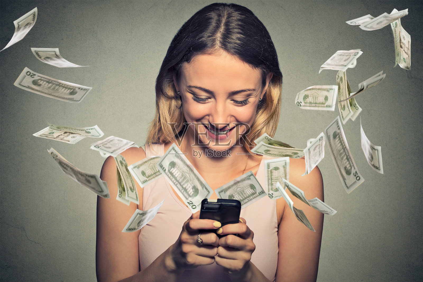 快乐的女人使用智能手机，钞票从屏幕上飞出照片摄影图片