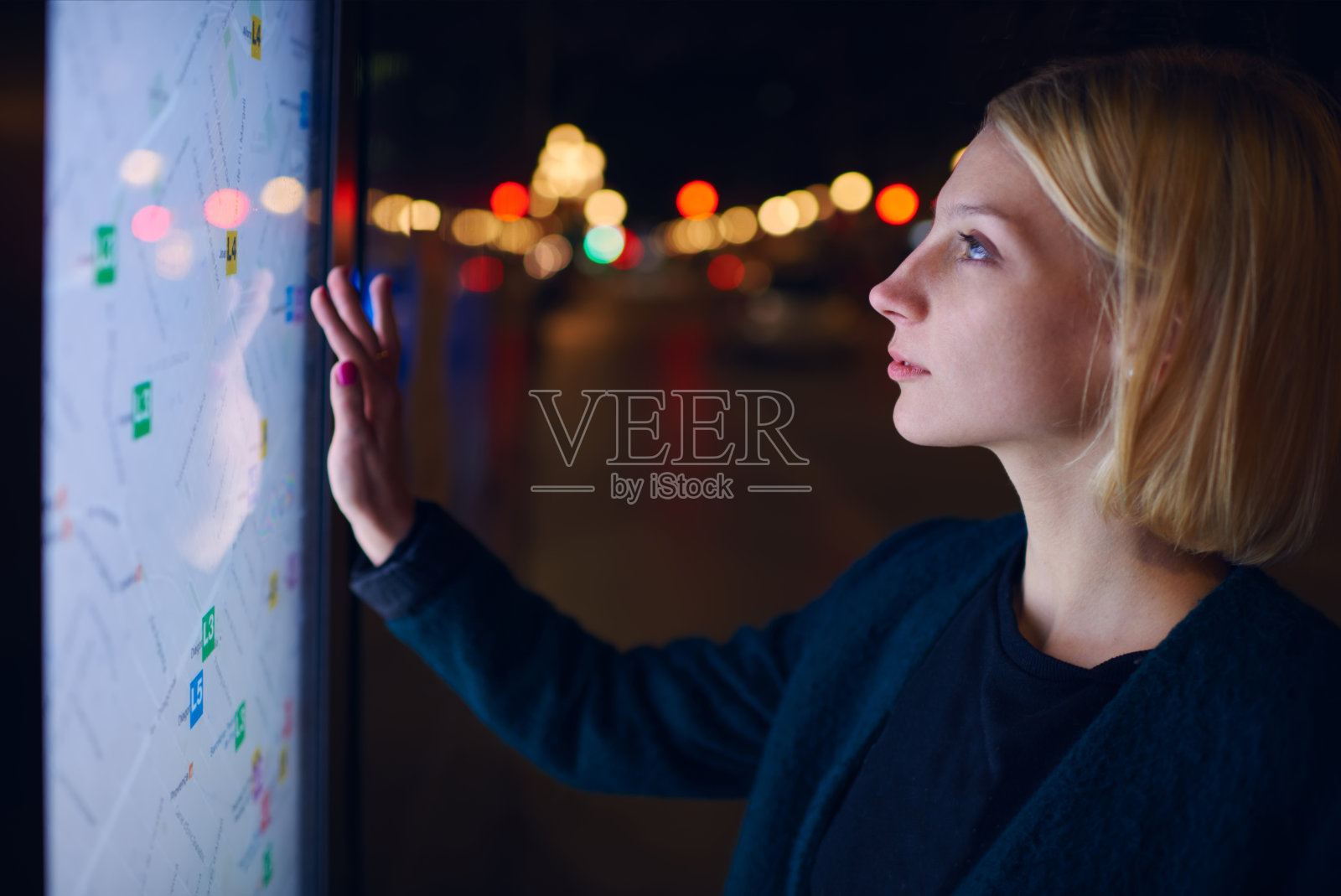 一个女人站在大屏幕前，上面有基本的城市地图照片摄影图片