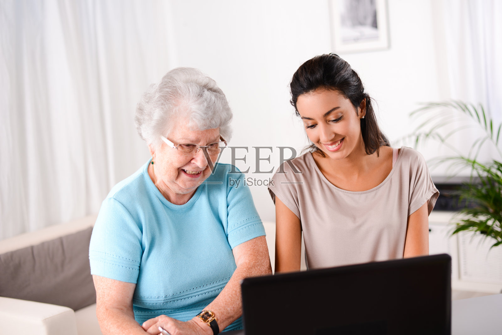 开朗的年轻女子教老人电脑和互联网照片摄影图片