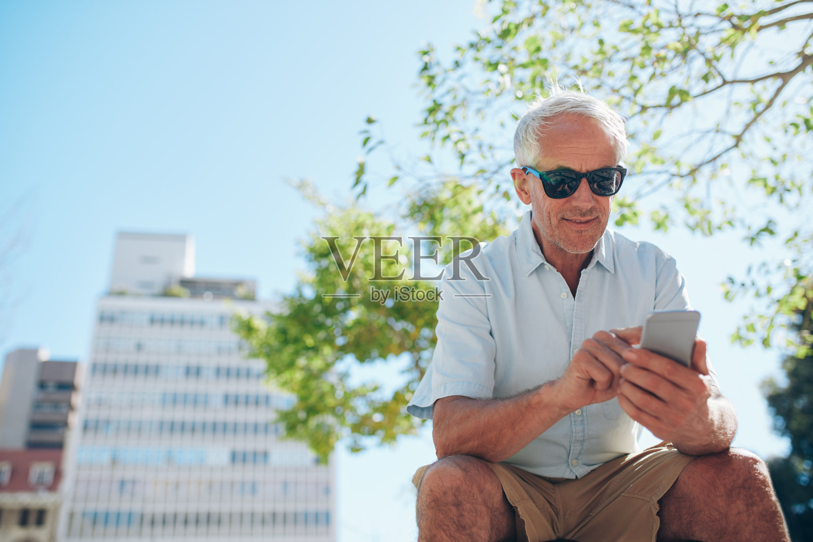 成熟的男人坐在户外玩手机照片摄影图片