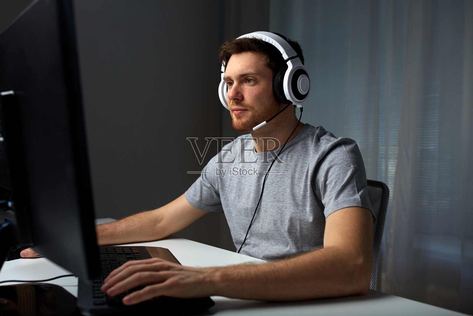 戴着耳机的男人在家里玩电脑游戏照片摄影图片