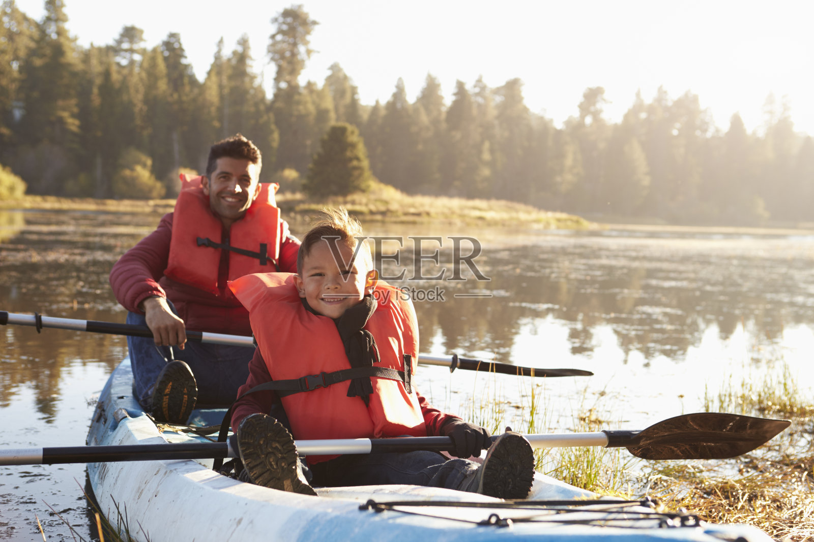 父亲和儿子皮划艇在农村的湖上，近距离照片摄影图片