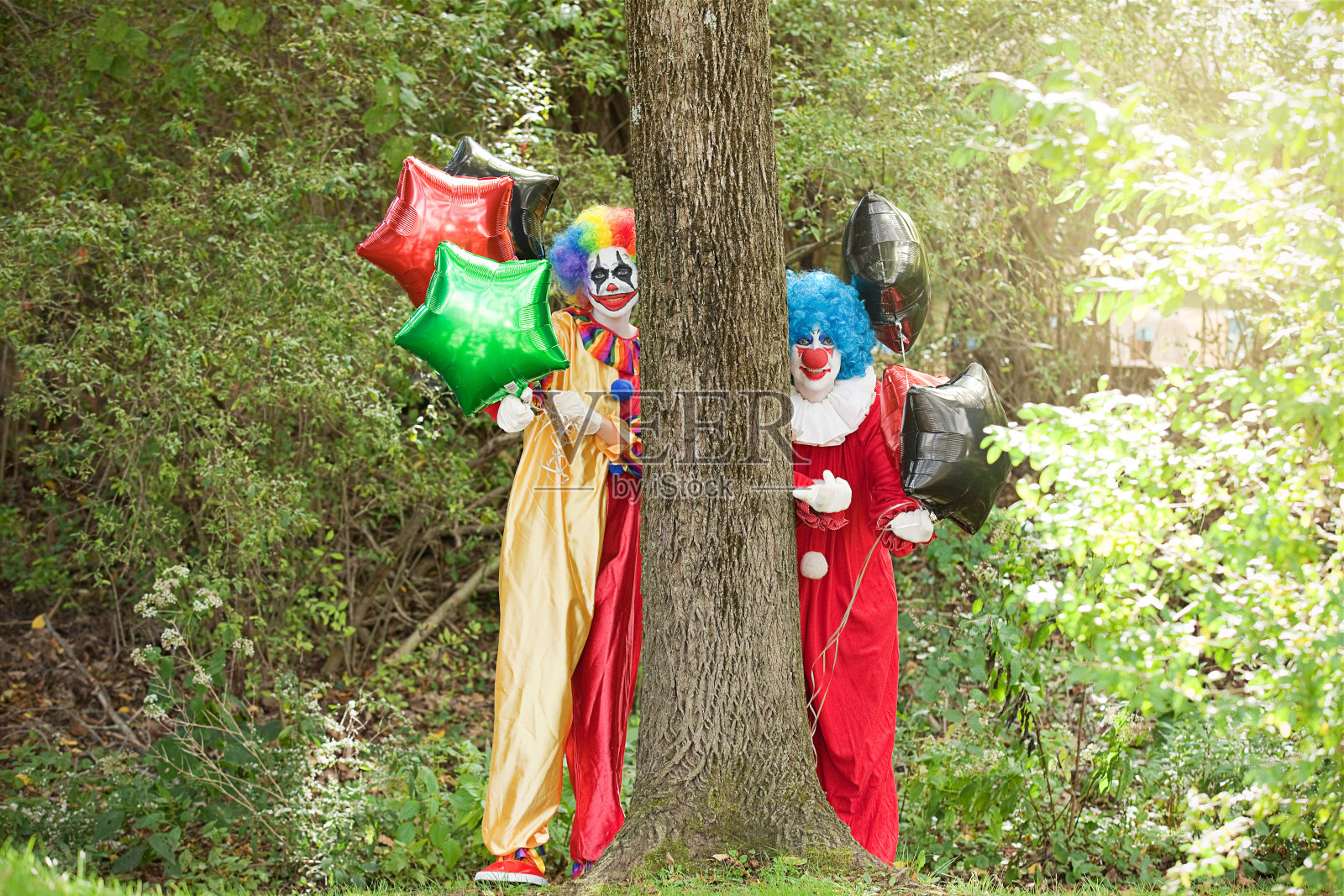 恐怖小丑用气球引诱人们进入森林照片摄影图片