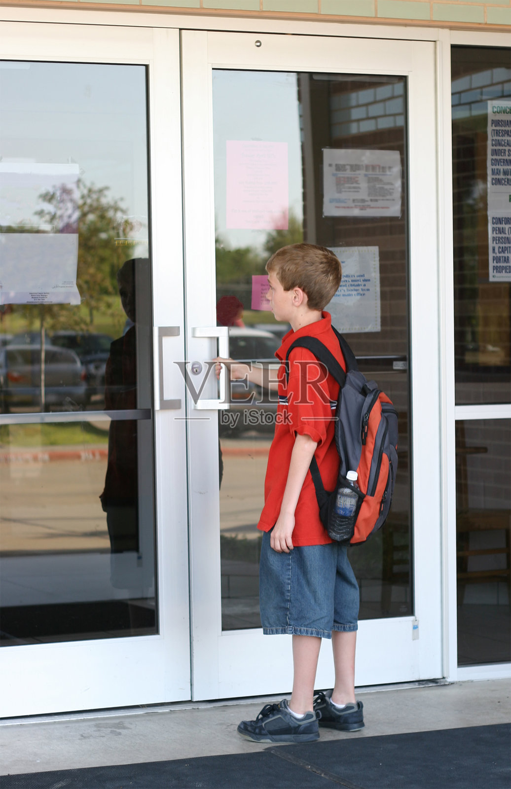 一个背着书包的小男孩打开了学校的门照片摄影图片