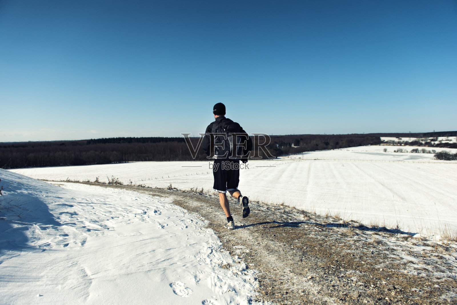 一个背着背包的人在雪地里跑步照片摄影图片