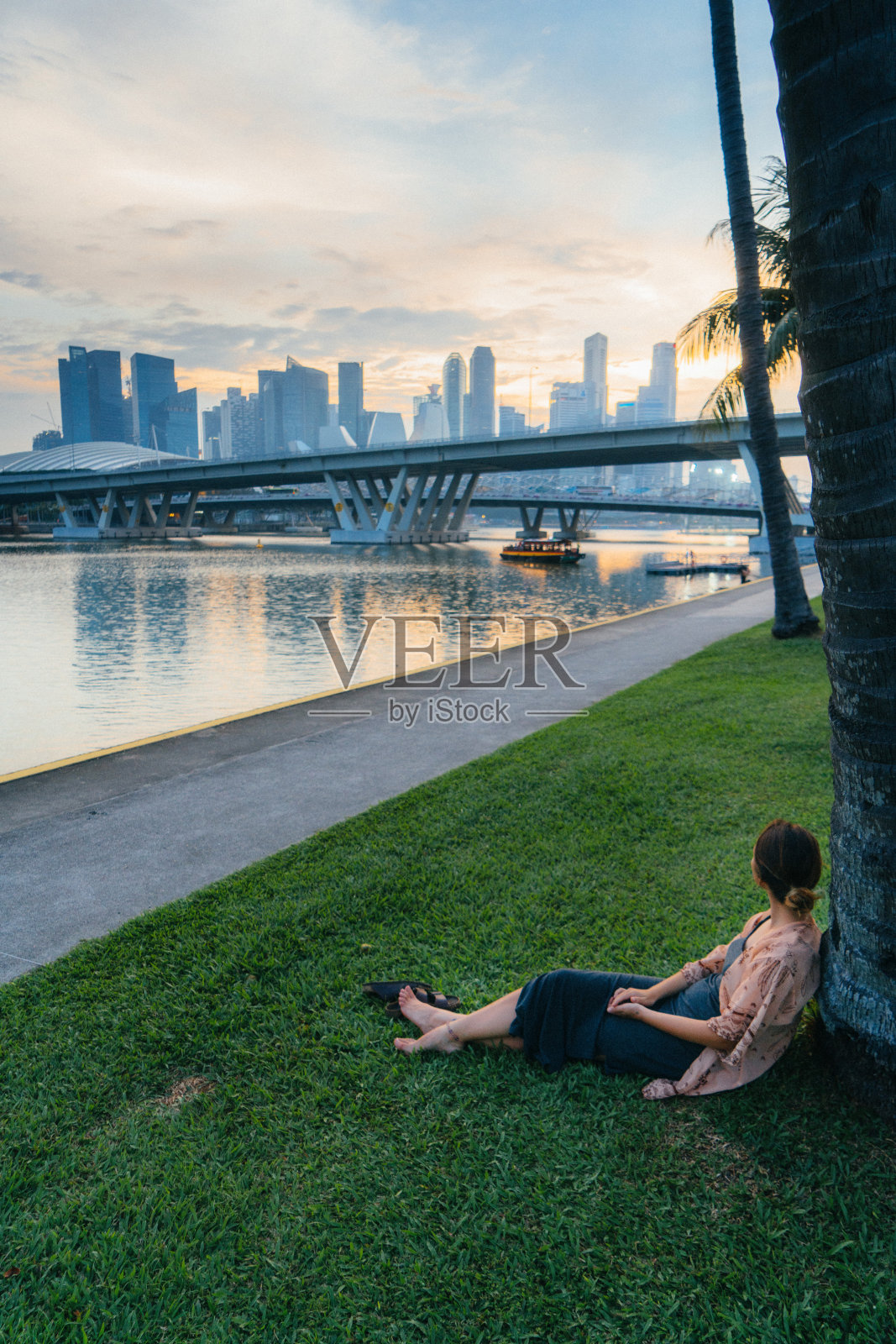 女人坐在草地上，看着新加坡照片摄影图片