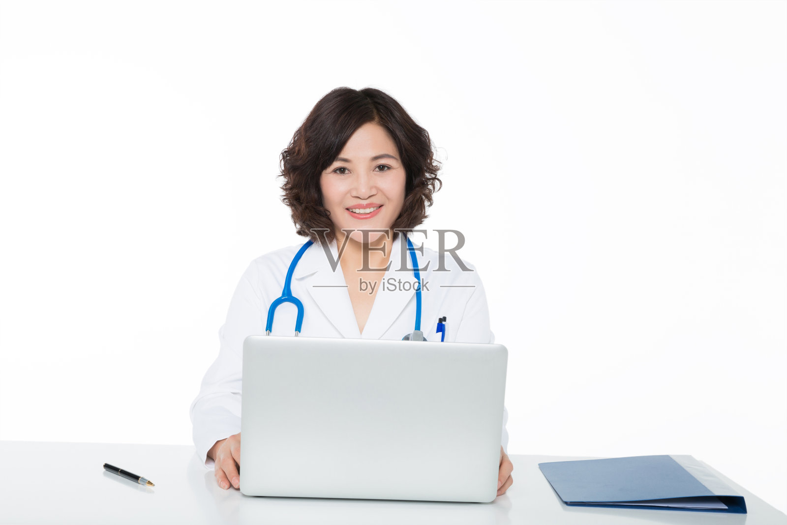女性成熟的医生用笔记本电脑和文件夹在办公桌上工作的肖像照片摄影图片