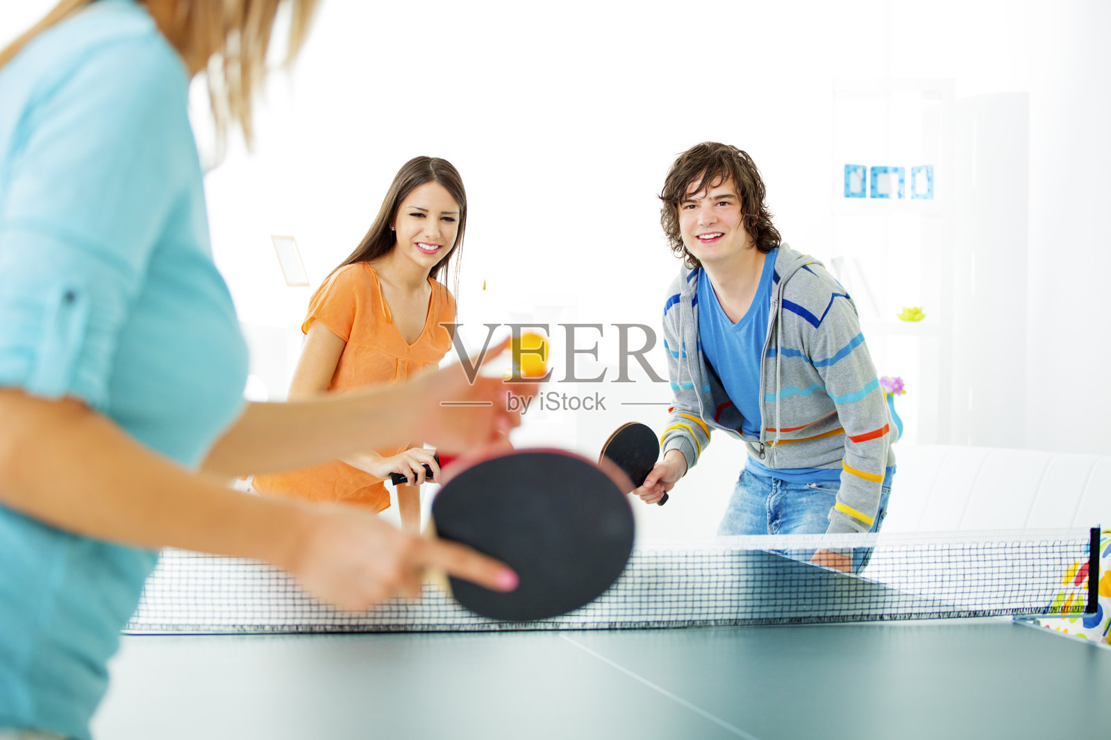 快乐的年轻人在打乒乓球。照片摄影图片