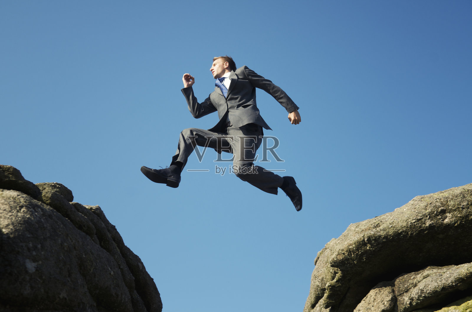 穿西装的人在高耸的岩石间跳跃照片摄影图片