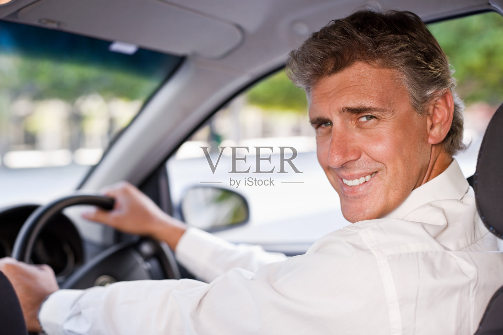 一个微笑的成熟商人驾驶汽车的肖像照片摄影图片