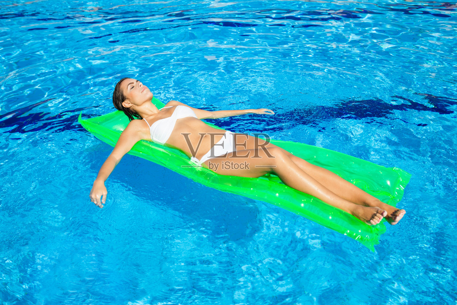 一个年轻女子在游泳池里晒日光浴照片摄影图片