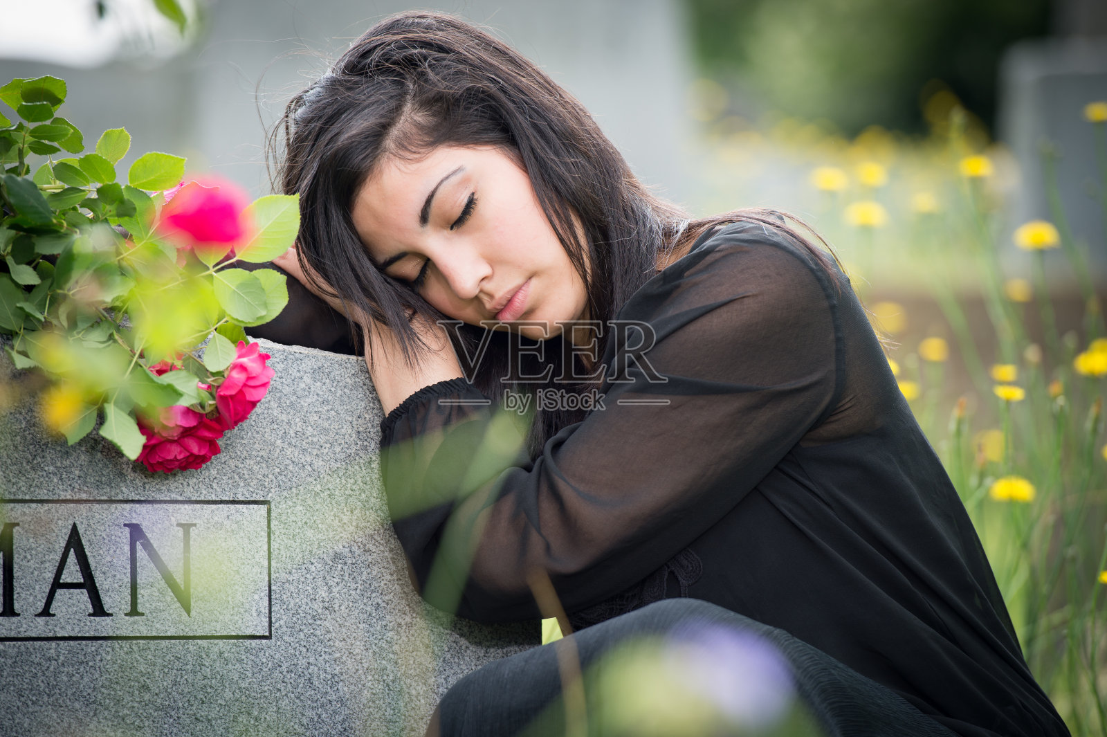 年轻女子在墓碑旁哀痛照片摄影图片