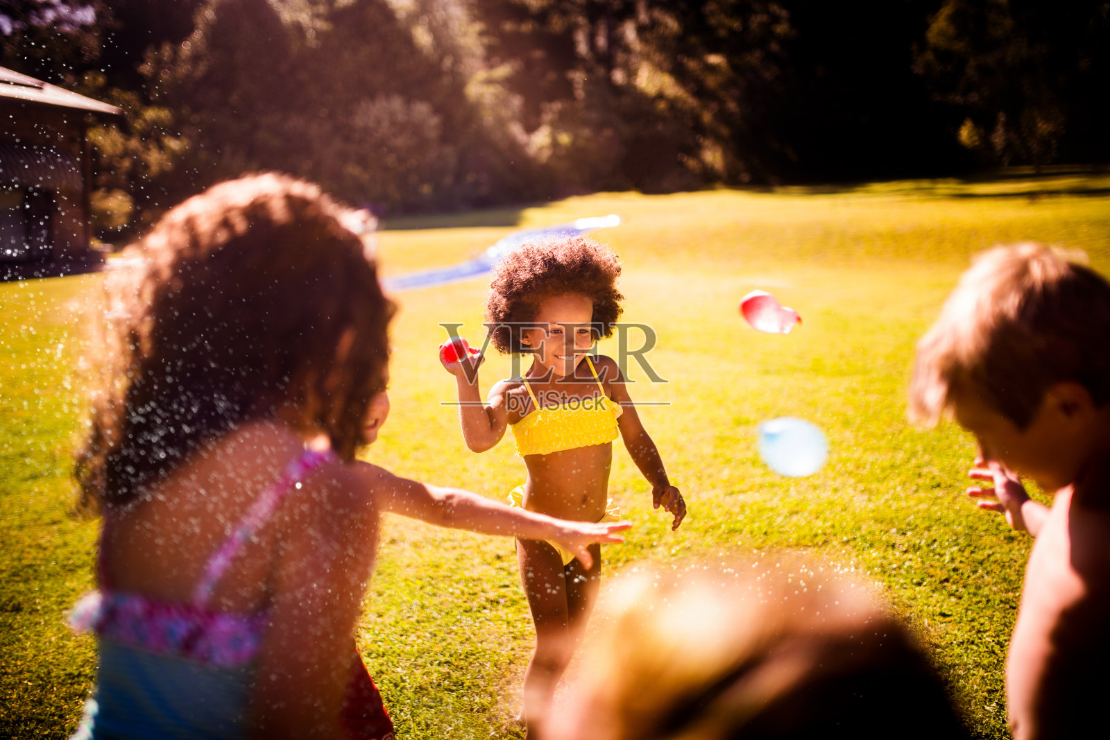 孩子们在阳光下互相扔水球照片摄影图片