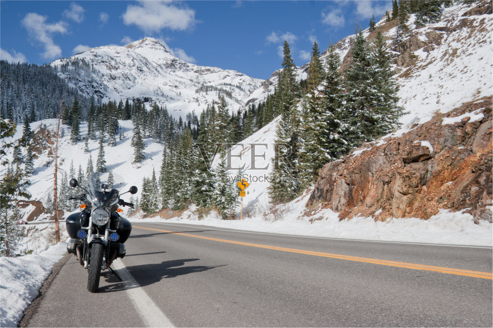 摩托车停在落基山脉积雪的公路上。照片摄影图片