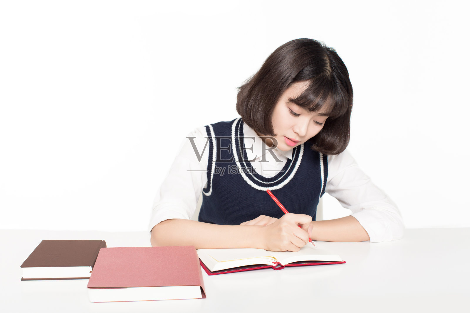 女孩坐在教室里，写着记录在她身上的书照片摄影图片
