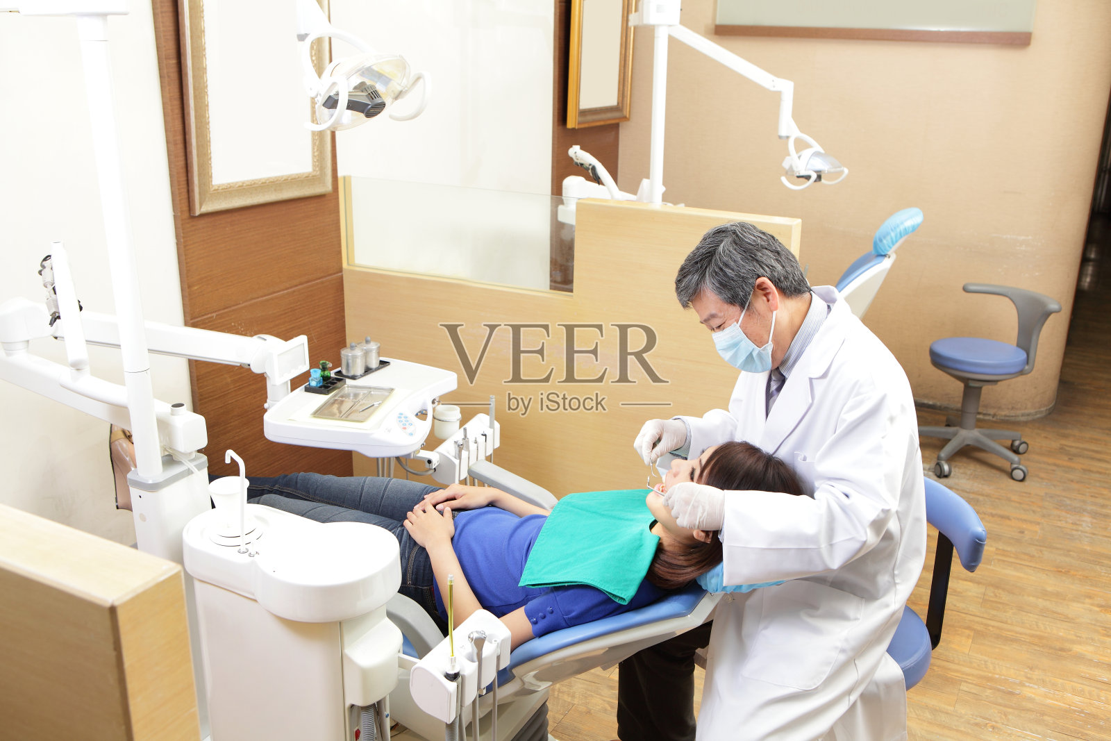 在牙科治疗中有牙医和助手的女病人照片摄影图片