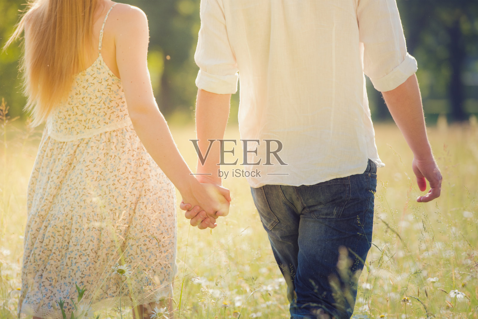 年轻的夫妇手牵着手走在草地上照片摄影图片