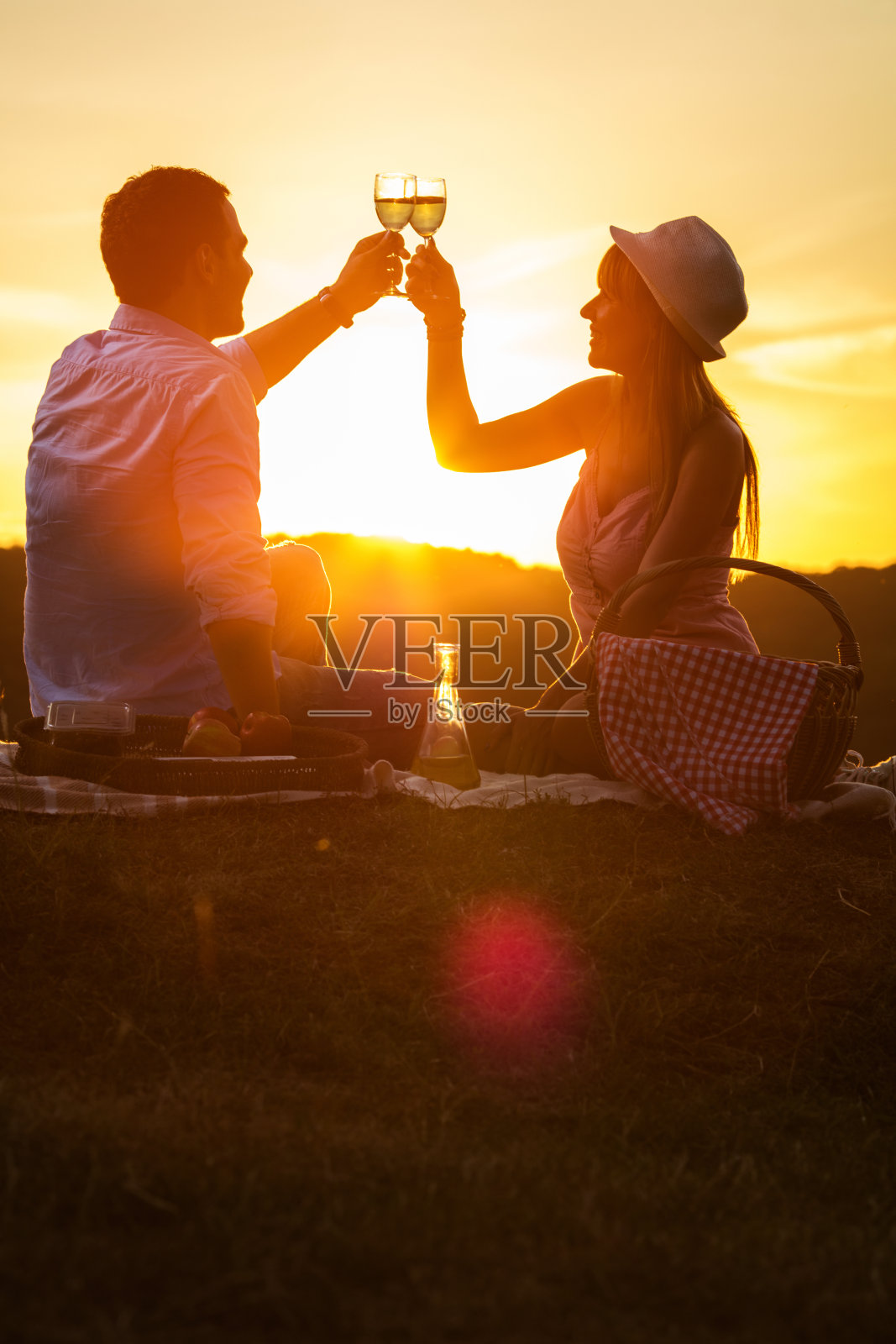 浪漫的夫妇在日落与葡萄酒干杯在日落。照片摄影图片