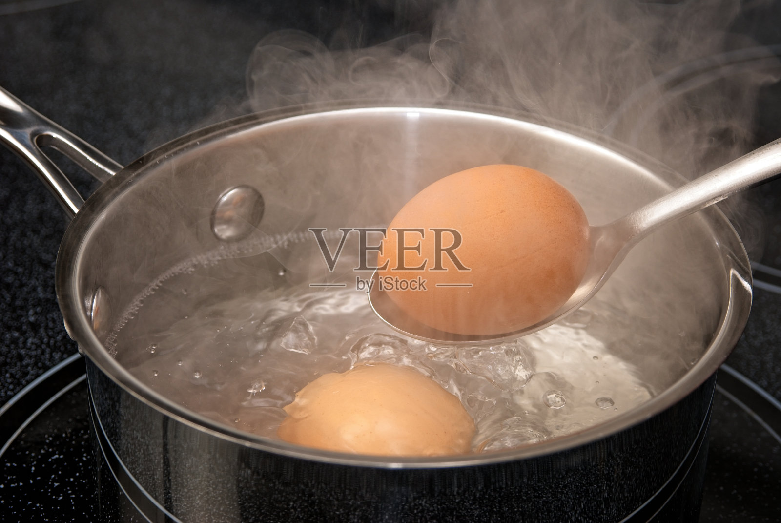 用一壶热气腾腾的水煮早餐鸡蛋。照片摄影图片