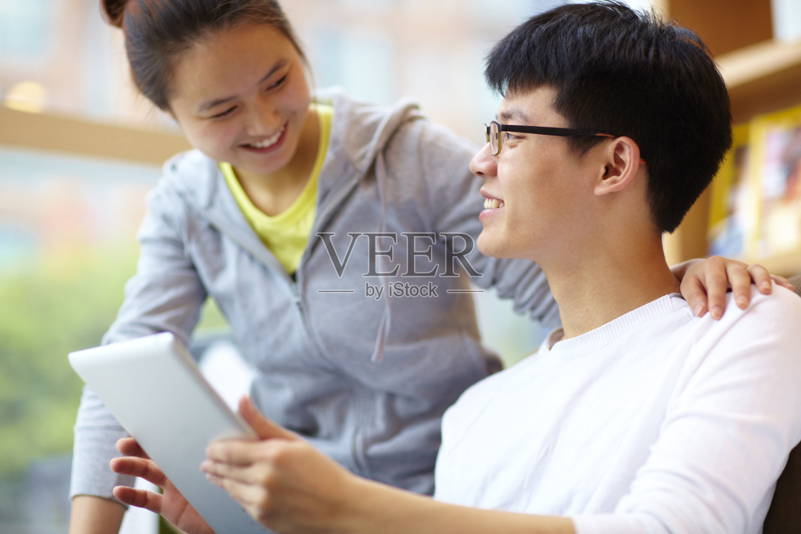 年轻的亚洲女人和她的男朋友在咖啡馆用平板电脑照片摄影图片